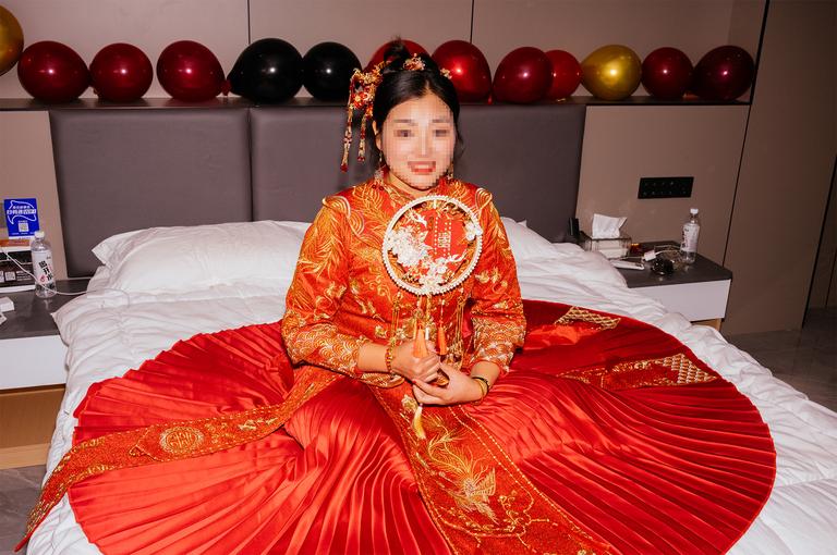 The bride in her wedding dress while her bridesmaids vet the groom and groomsmen. Her face has been pixelated for privacy.