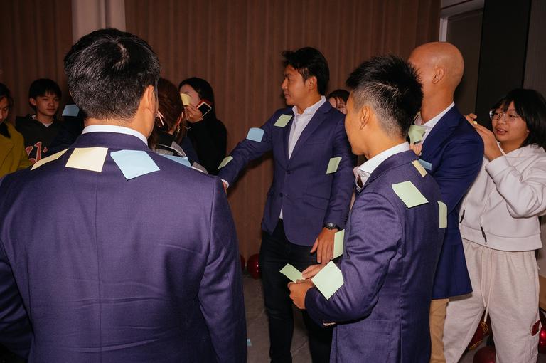 Sticky notes being placed on the groomsmen prior to the challenge. They had to get all of them off without using their hands or arms. The groomsmen narrowly met their deadline.